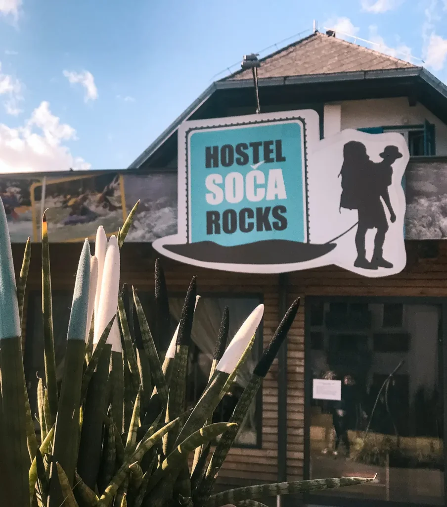 Vhod v Hostel Soča Rocks v Bovcu z napisom in lesenim pročeljem.