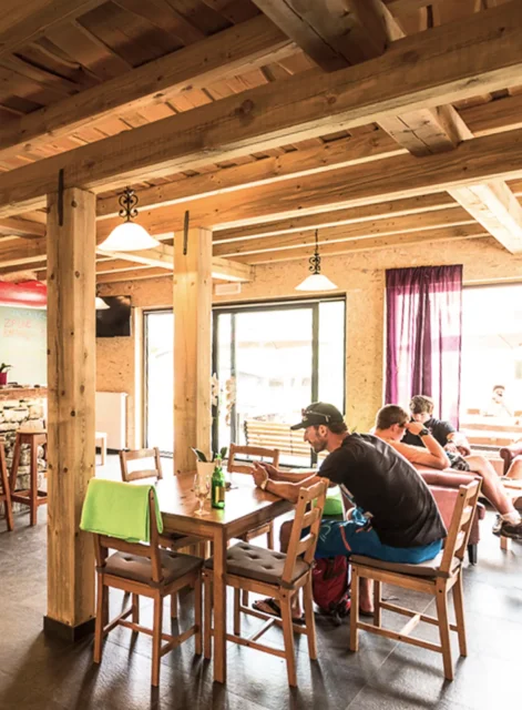 Lesen skupni prostor v Hostlu Soča Rocks z mizami in gosti, ki počivajo po aktivnostih.