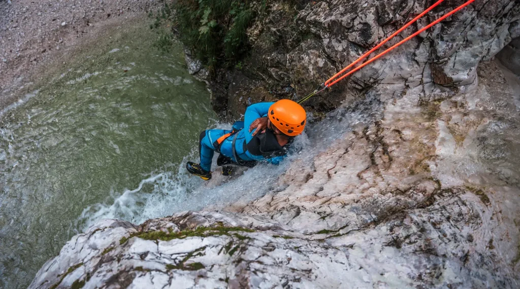 Kanjonist se ob vrvi spušča po slapu v ozki soteski, del kombiniranega paketa doživetij.
