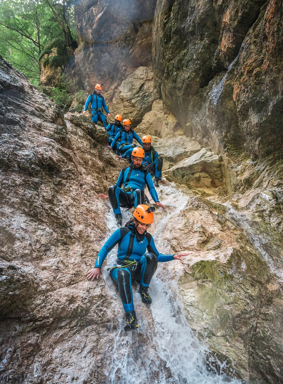 Skupina drsi po naravnem toboganu na team building kanjoningu pri Bovcu.