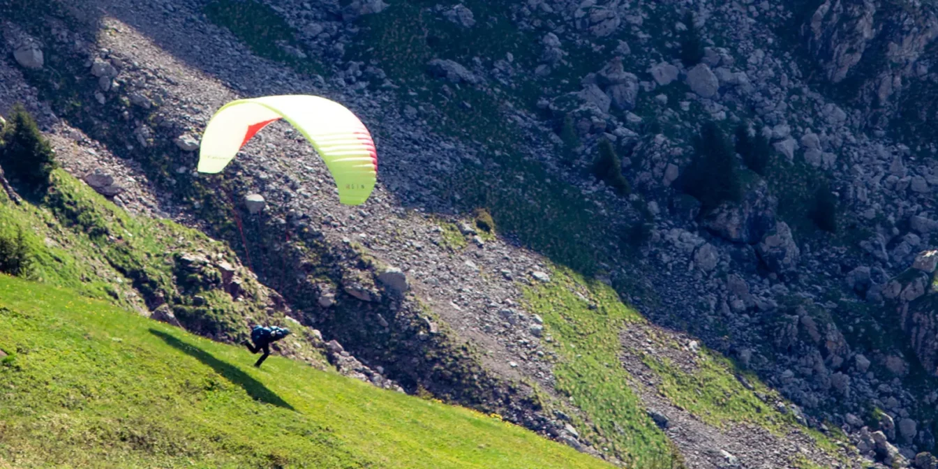 Pilot z jadralnim padalom med zaletom z gorskega pobočja nad Bovcem