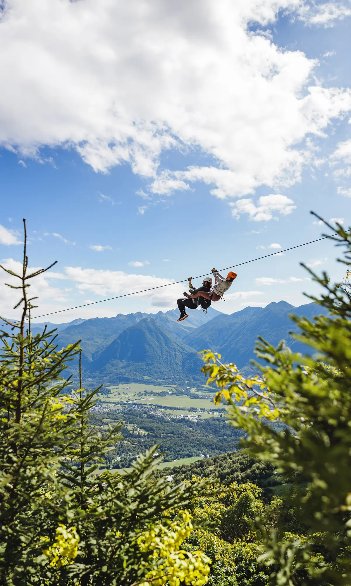 Zipline Bovec: obiskovalec drvi po jeklenici visoko nad dolino Krnice, v ozadju vrhovi Julijcev in Bovška kotlina.